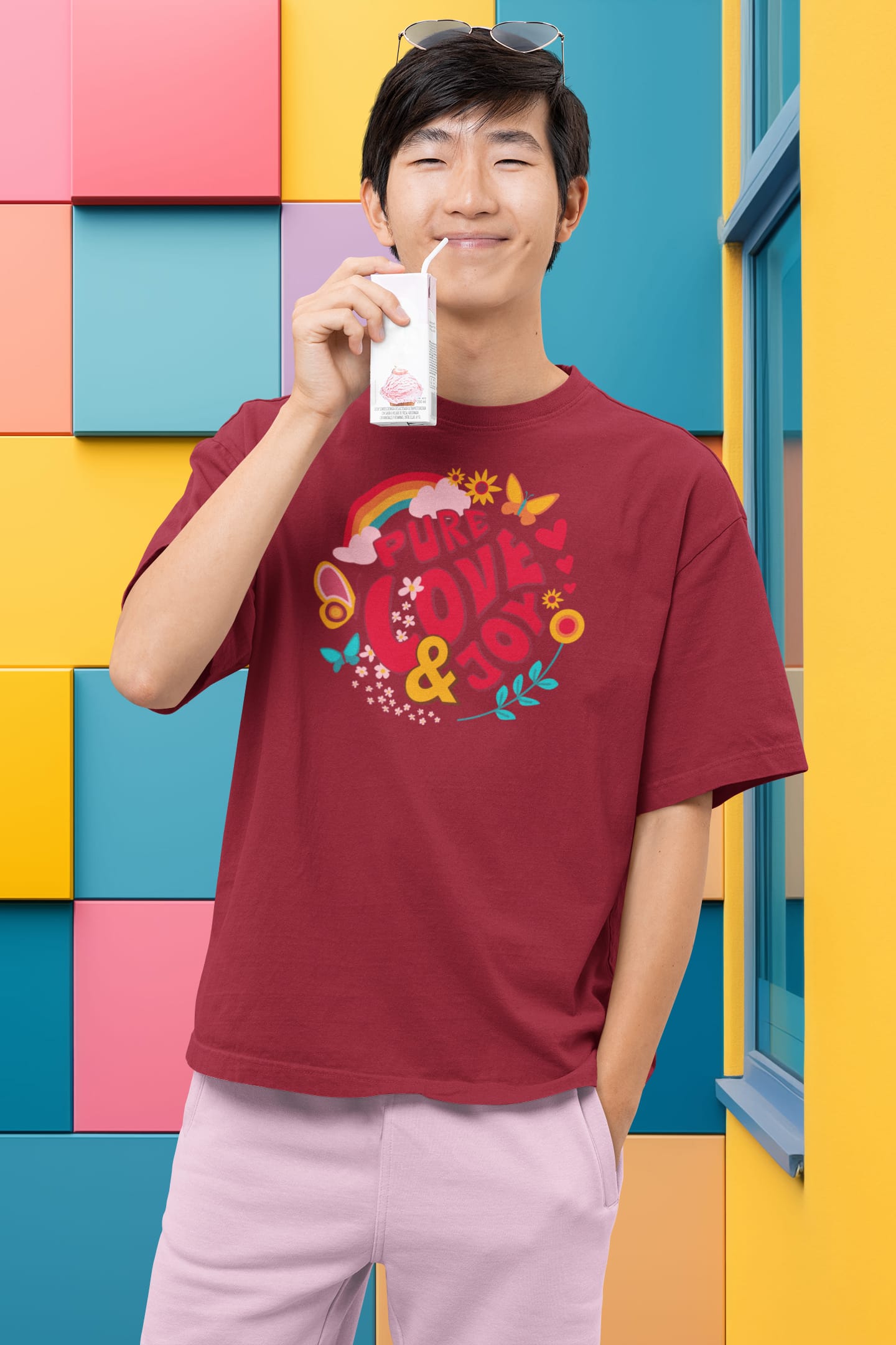 "Pure Love and Joy" Print on red T-Shirt. Asian male posing with soft drink in front of colorful background.